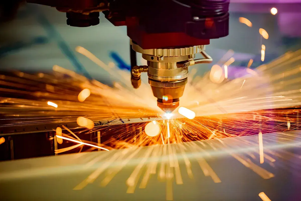 Laser cutting head throwing orange sparks as it cuts metal, CNC technology